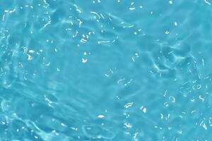 Blue water with ripples on the surface. Defocus blurred transparent blue colored clear calm water surface texture with splashes and bubbles. Water waves with shining pattern texture background. photo