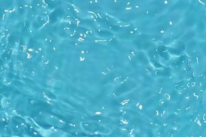 Blue water with ripples on the surface. Defocus blurred transparent blue colored clear calm water surface texture with splashes and bubbles. Water waves with shining pattern texture background. photo