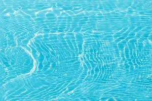 Blue water with ripples on the surface. Defocus blurred transparent blue colored clear calm water surface texture with splashes and bubbles. Water waves with shining pattern texture background. photo