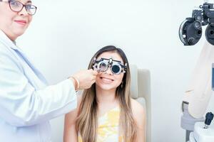 Female optometrist examining patient with optometrist trial frame. Smiling patient with optometrist trial frame photo