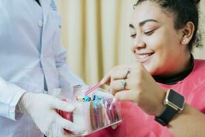 Dental patient choosing dental braces, Patient with dentist choosing colored rubber band. Patient with dentist choosing dental braces photo