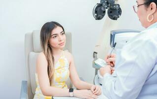 Female patient having consultation with optometrist in office. Optometrist with female patient taking notes in office. photo