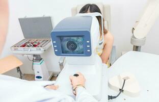 Optometrist using refractometer with patient. Eyesight of a patient on the screen of the refractometer photo