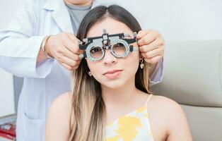 manos de optometrista examinando paciente con optometrista juicio marco. joven paciente con optometrista juicio marco foto