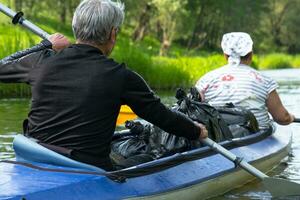 Family kayak trip for seigneur and senora. An elderly married couple rowing a boat on the river, a water hike, a summer adventure. Age-related sports, mental youth and health, tourism, active old age photo