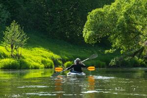 Family kayak trip for seigneur and senora. An elderly married couple rowing a boat on the river, a water hike, a summer adventure. Age-related sports, mental youth and health, tourism, active old age photo