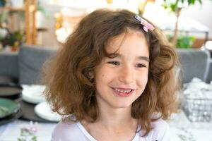 Portrait of a happy baby girl with a perky and mischievous smile close-up with short curly hair. photo