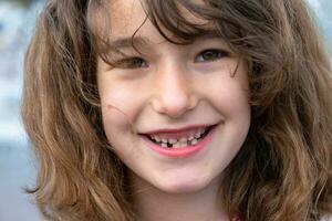 sin dientes contento sonrisa de un niña con un caído inferior Leche diente de cerca. cambiando dientes a molares en infancia foto