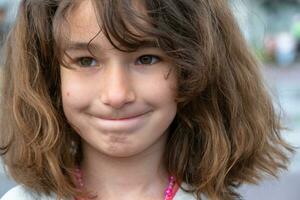 Portrait of a happy baby girl with a perky and mischievous smile close-up with short curly hair. photo