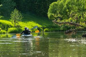 Family kayak trip for seigneur and senora. An elderly married couple rowing a boat on the river, a water hike, a summer adventure. Age-related sports, mental youth and health, tourism, active old age photo