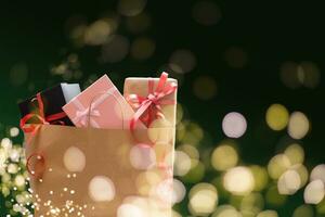 Holiday shopping bags and gift boxes on dark background, light bokeh photo