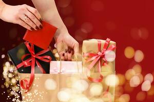 Shimmer background, light bokeh. Woman hands packages with gifts box. Christmas, new year, birthday concept. Banner, copy space. photo