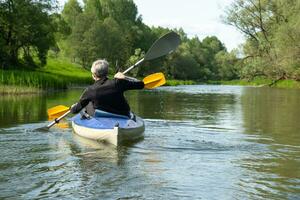 Family kayak trip for seigneur and senora. An elderly married couple rowing a boat on the river, a water hike, a summer adventure. Age-related sports, mental youth and health, tourism, active old age photo