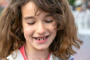 Toothless happy smile of a girl with a fallen lower milk tooth close-up. Changing teeth to molars in childhood photo