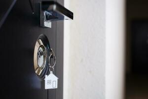 Silhouette of door keys hanging on the open door with blurred background photo