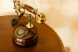 Retro phone on a wooden table. Vintage telephone of brown and golden color, white background photo