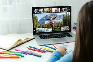 Young Woman Sitting Near The Sofa Watching Video On Laptop photo