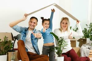 Happy family sitting on wooden floor. Father, mother and child having fun together. Moving house day, new home and design interior concept photo