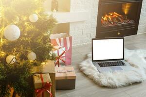 laptop stands near the fireplace and Christmas tree photo