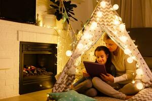 Elegant mother in a white sweater. Family with cristmas gifts. Little girl near the fireplace photo