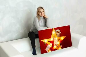 Young girl holds photo canvas at home on the couch