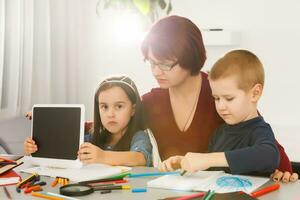 Teacher and kids lying on floor using digital tablet in library at elementary school photo