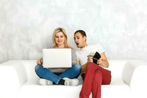 Young couple lying on the sofa, shopping online photo