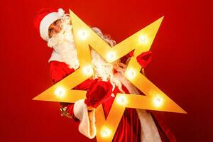 Funny santa claus with big star in Christmas on red background photo