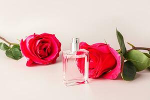 un hermosa botella de perfume o cosmético rociar en el antecedentes de un cortar rojo té Rosa. el concepto de perfumería y belleza. blanco botella disposición. foto