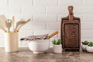 cocina utensilios hecho de ambientalmente simpático materiales en un moderno mármol encimera con interior flores blanco ladrillo pared. foto