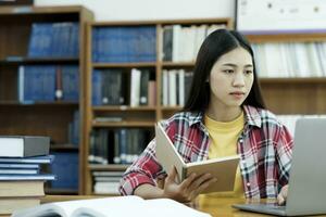 Young university student using laptop for online learning, searching and learning at library. photo