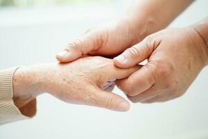 Caregiver holding hands Asian elderly woman patient, help and care in hospital. photo