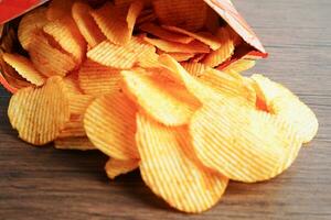 papas fritas en bolsa abierta, delicioso condimento de barbacoa picante para crips, refrigerio frito en rodajas finas comida rápida. foto