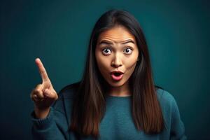 Surprised beautiful girl pointing finger over blue background photo