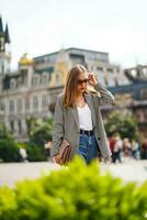 Girl walking through historic city area. Woman wearing sunglasses looks down. Girl walks around city against background of beautiful architectural buildings. Batumi City in Georgia photo