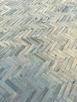 Old tiles on the ground. Zigzag tiling. Abstract background with old stones. Light colors. Vertical composition. Textured gray background. Mosaic floor tiles in rectangles in shades of gray and white photo