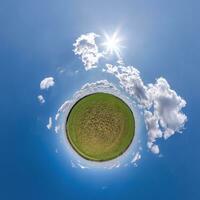 green tiny planet in blue sky with beautiful clouds with transformation of spherical panorama 360 degrees. Curvature of space. photo