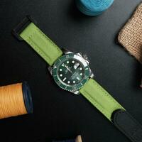 Surabaya, IDN, 2023 - Luxury watch with green dial, bright green canvas strap on a dark background and sewing thread accessories photo