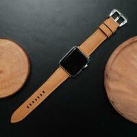 Surabaya, IDN, 2023 - Photography of a smartwatch with a light brown strap, against a dark background and wood cutout photo