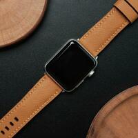 Surabaya, IDN, 2023 - Photography of a smartwatch with a light brown strap, against a dark background and wood cutout photo