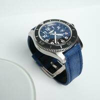 Surabaya, IDN, 2023 - Product photo of a luxury watch with a blue jeans canvas strap with a shiny white board background