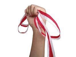 The hands of a man holding a red and white ribbon as a symbol of the Indonesian flag. Isolated on white background photo