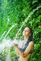 a woman in a bikini is splashing water on her head photo