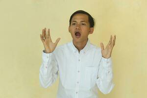 the man in the white shirt was surprised to be seen from his face who felt shocked by raising both hands isolated on a yellow background photo