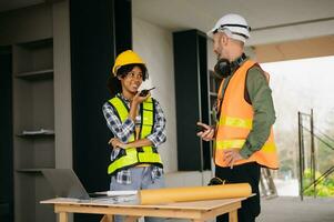 Architect caucasian man and woman working with colleagues mixed race in the construction site. Architecture engineering on big project. Building in construction process interior. photo