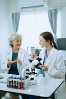 Two scientist or medical technician working, having a medical discuss meeting with an Asian senior female scientist supervisor in the laboratory with online reading, test samples and innovation photo