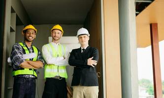 Architect caucasian man working with colleagues mixed race in the construction site. Architecture engineering on big project. Building in construction process interior. look at camera photo