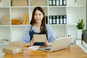 retrato de asiático joven mujer SME trabajando utilizando teléfono inteligente o tableta tomando recibir y comprobación en línea compra compras orden a negocio en línea concepto. foto