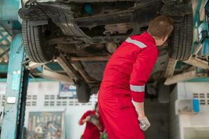 Caucasian repairmen are analyzing and fixing broken car in car repair mechanic shop photo