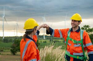 Smart engineers with protective helmet giving fist bump at electrical turbines field photo